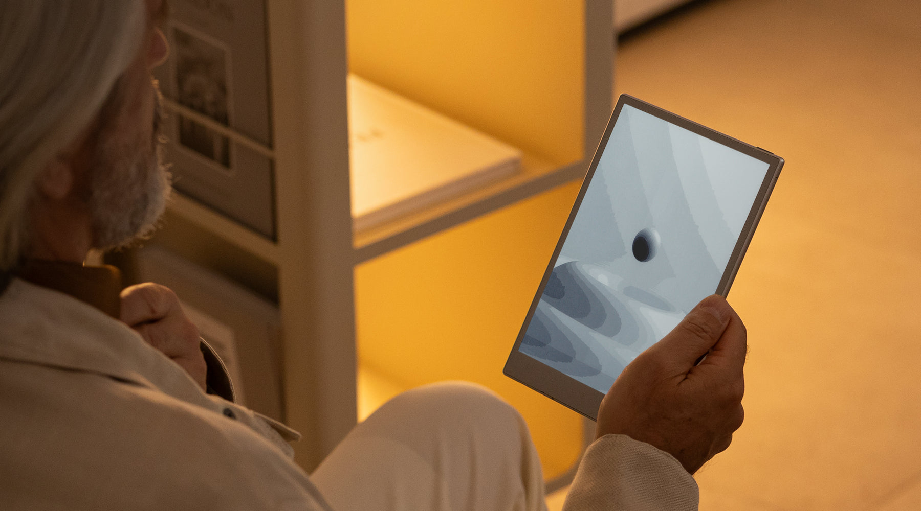 Person holding a paper tablet with a screen displaying an image of a black hole, in a warm indoor setting.