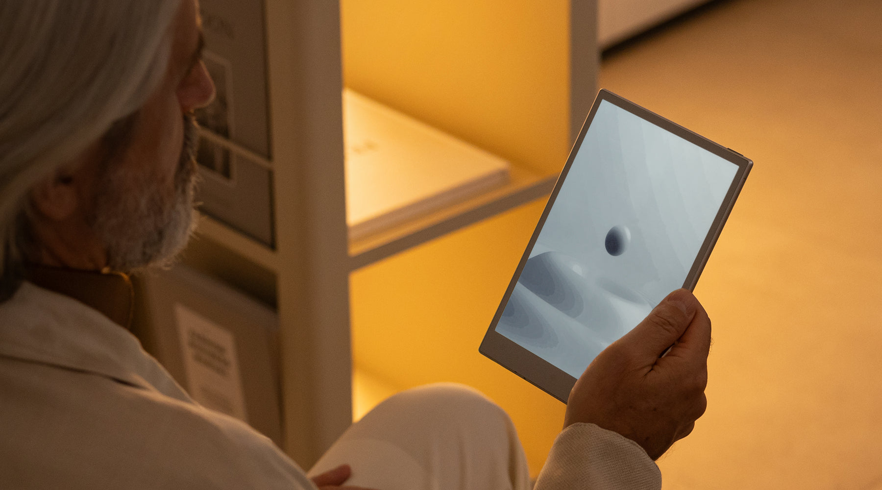 Person holding a tablet with a screen displaying an image of a black hole in a warmly lit room.