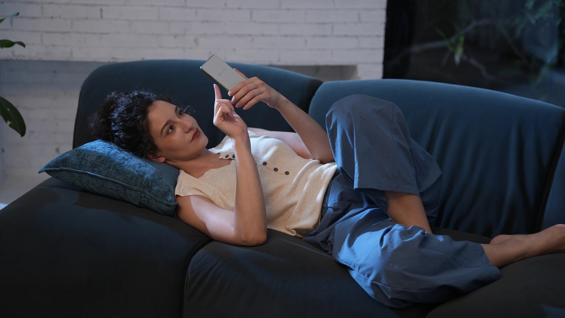 Woman lying on a couch holding an AiPaper reader C in a dimly lit room.